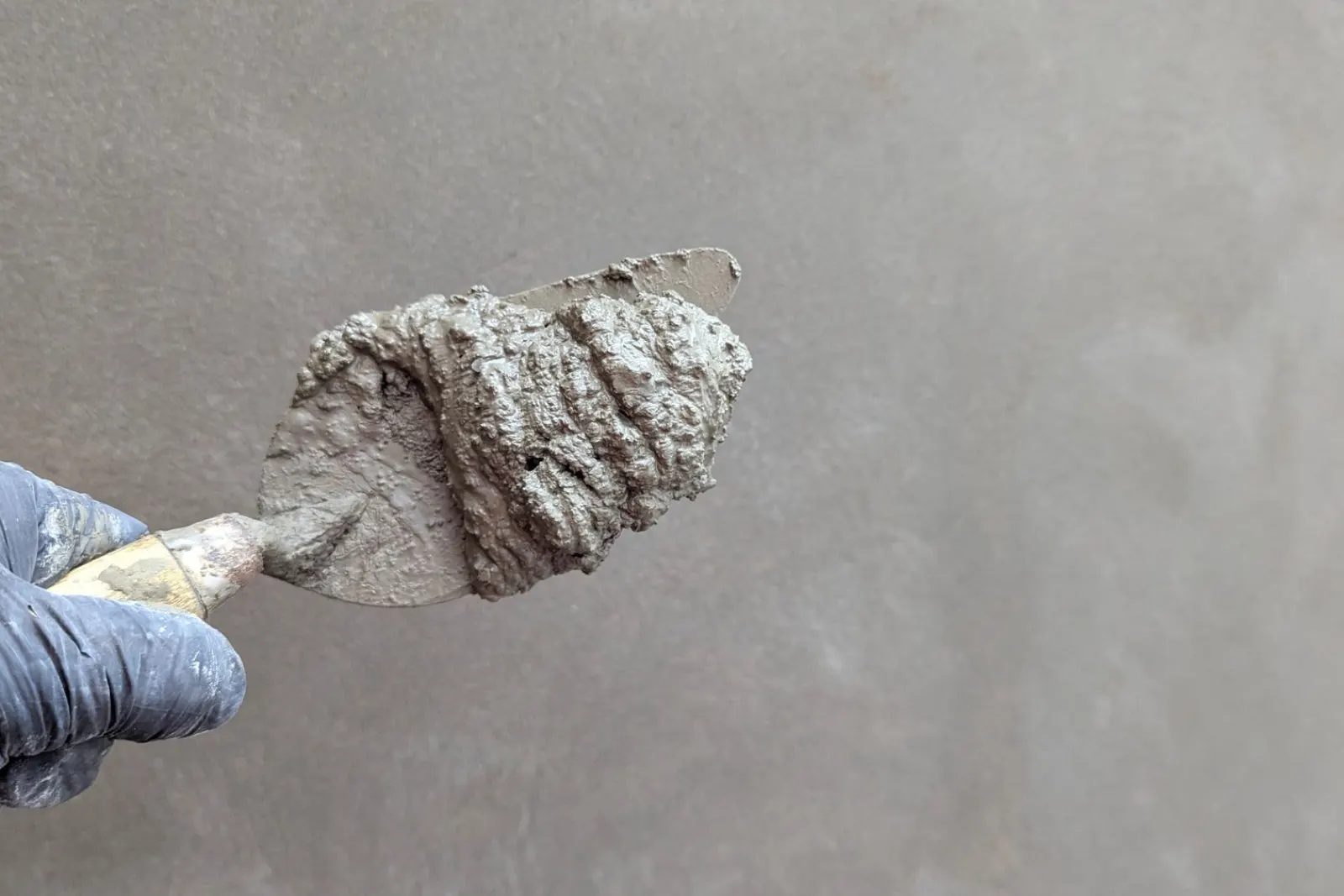 A trowel spreading finish plaster across a wall